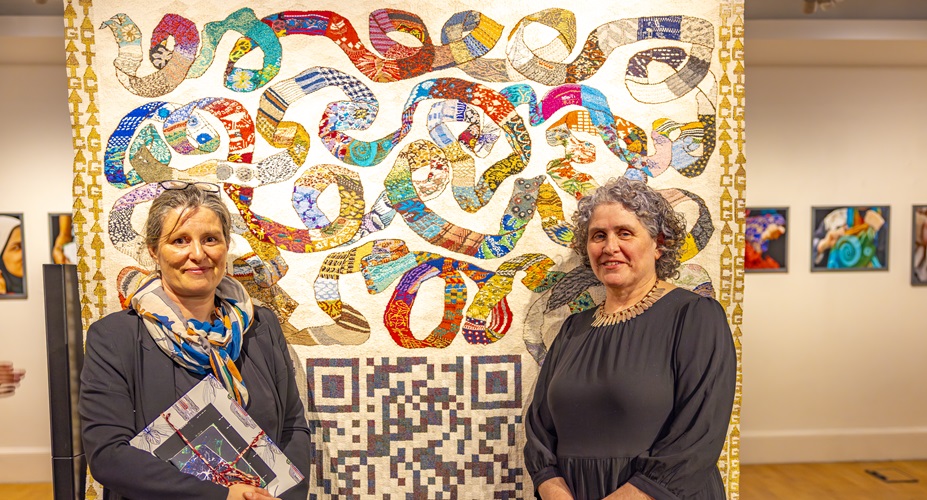 Women smiling in front of tapestry